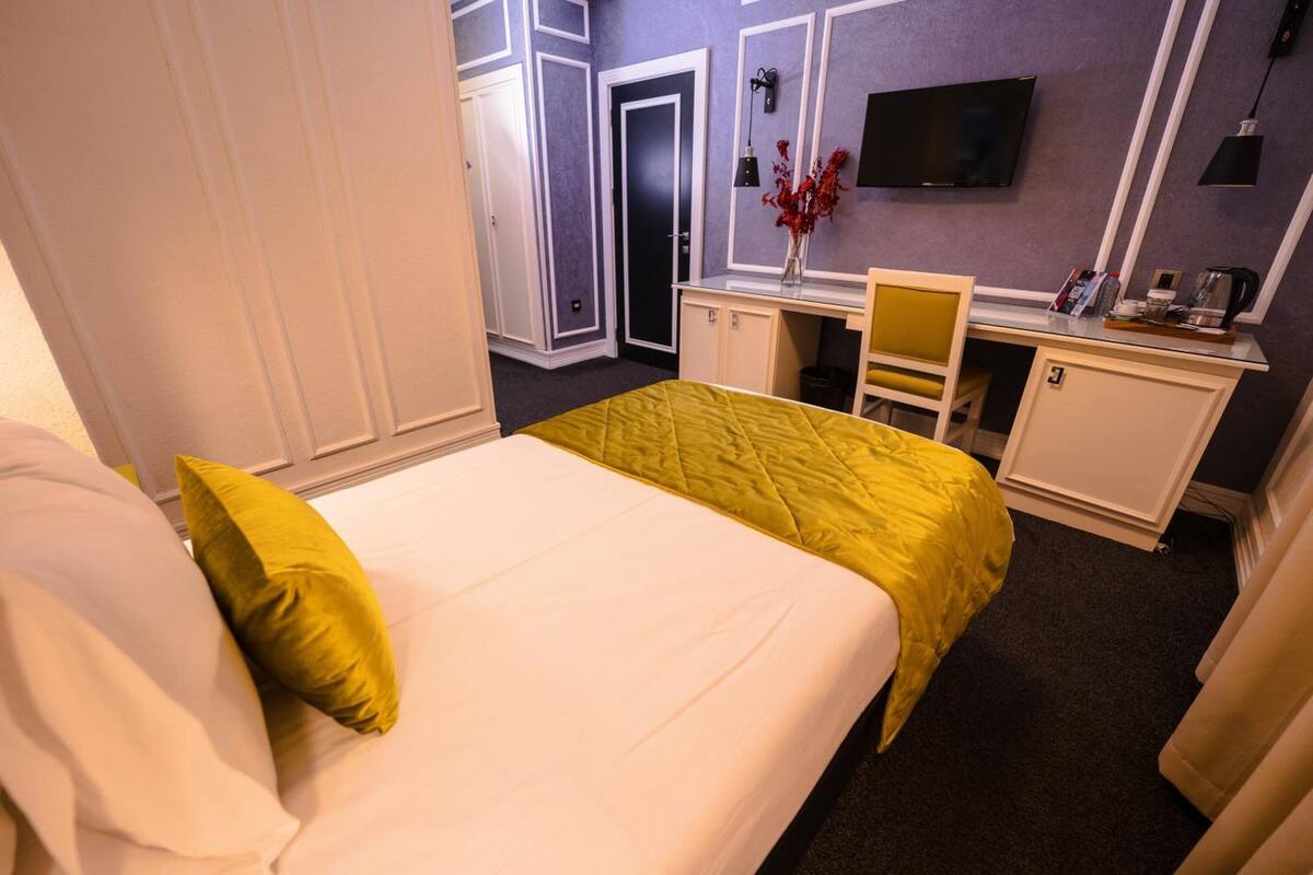 A hotel room with a bed, a desk, a chair, and a TV.