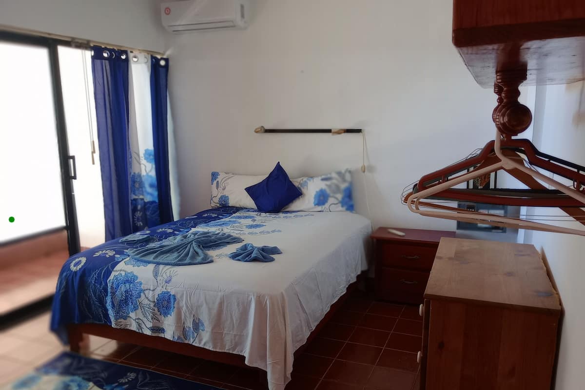 Een slaapkamer met een bed, een houten dressoir, een nachtkastje en een kledingrek.