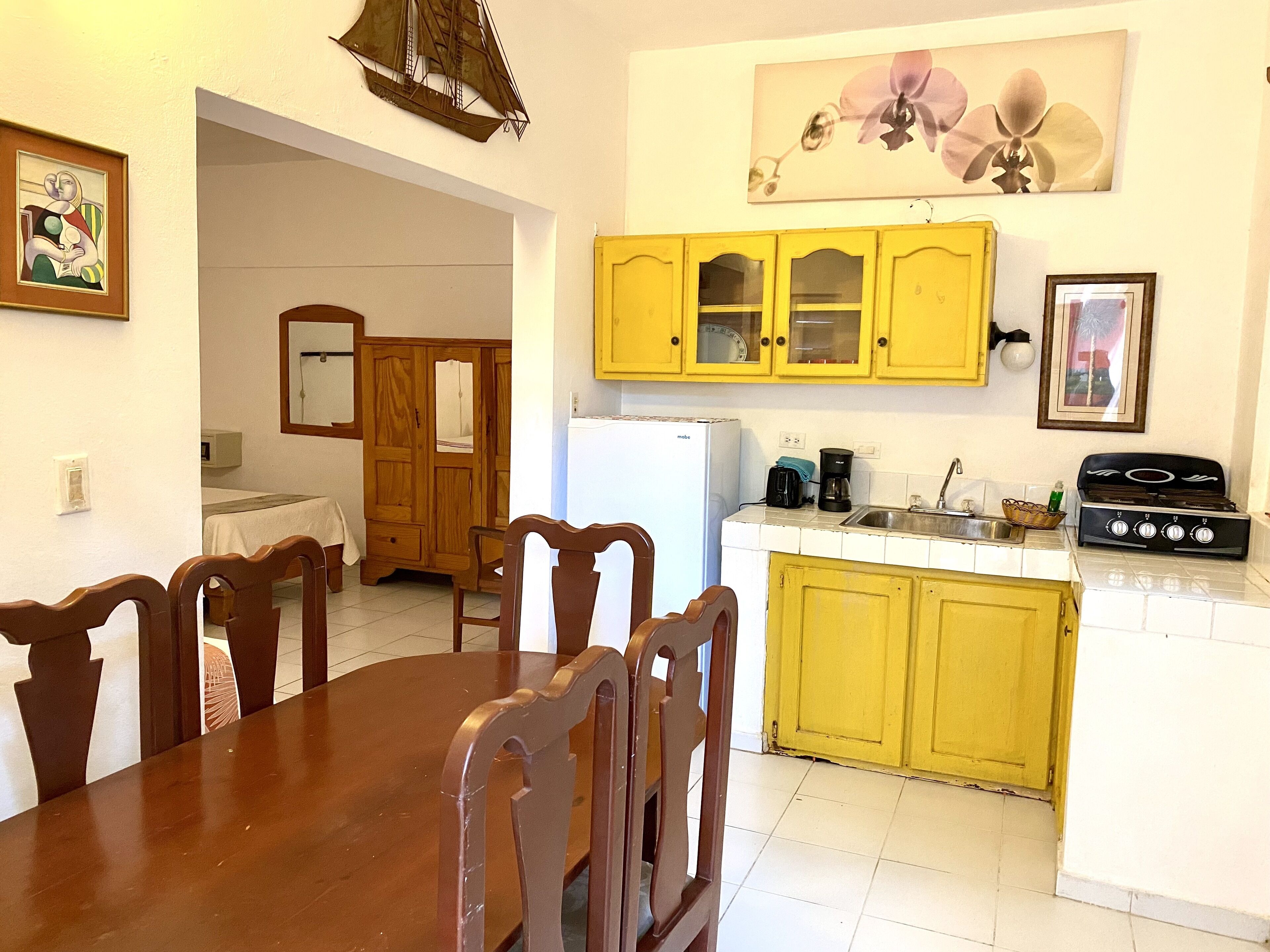 A compact kitchen with yellow cabinets, a white refrigerator, and a gas stove.