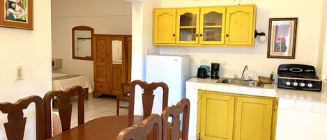 A compact kitchen with yellow cabinets, a white refrigerator, and a gas stove.