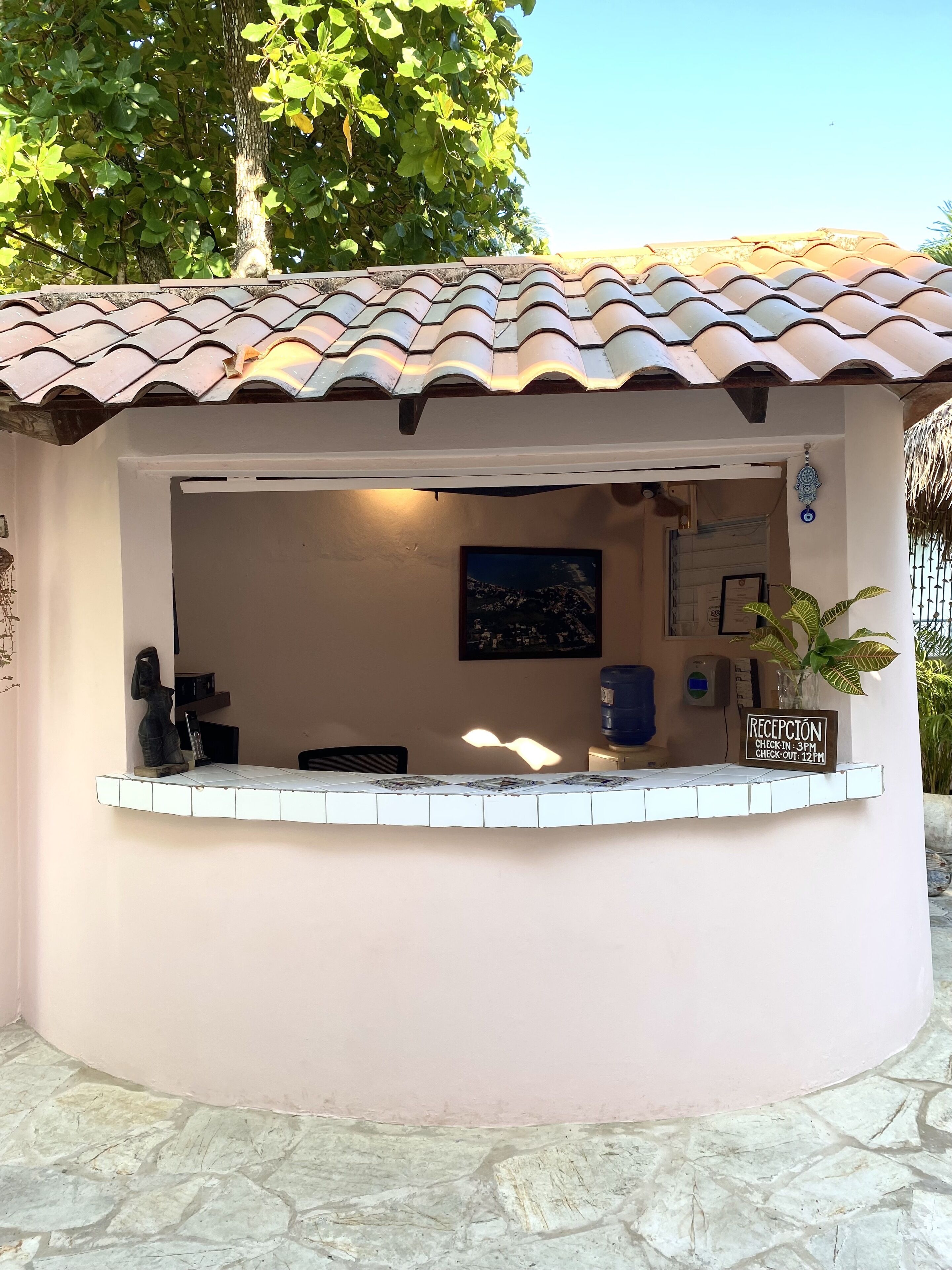 A reception area with a tiled roof, a reception desk, a framed picture on the wall, and a water dispenser.