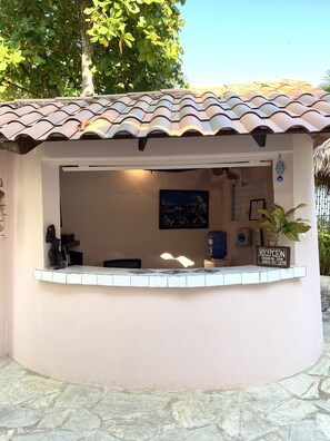 Un espace d’accueil doté d’un toit en tuiles, d’un comptoir de réception, d’un tableau encadré au mur et d’un distributeur d’eau.