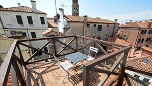 A rooftop terrace with a wooden deck, a table, and chairs. - ARNOLDI-Rooftop (Venice)
