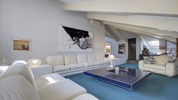 A modern living room with a sectional sofa, a coffee table, and a painting on the wall. - ARNOLDI-Rooftop (Venice)