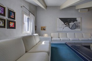 A modern living room with a sofa, a coffee table, and a painting on the wall.
