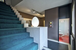 A staircase with blue steps leading to a landing with a white circular light fixture. - ARNOLDI-Rooftop (Venice)