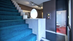 A modern staircase with blue steps leading to a landing with a white circular light fixture. - ARNOLDI-Rooftop (Venice)