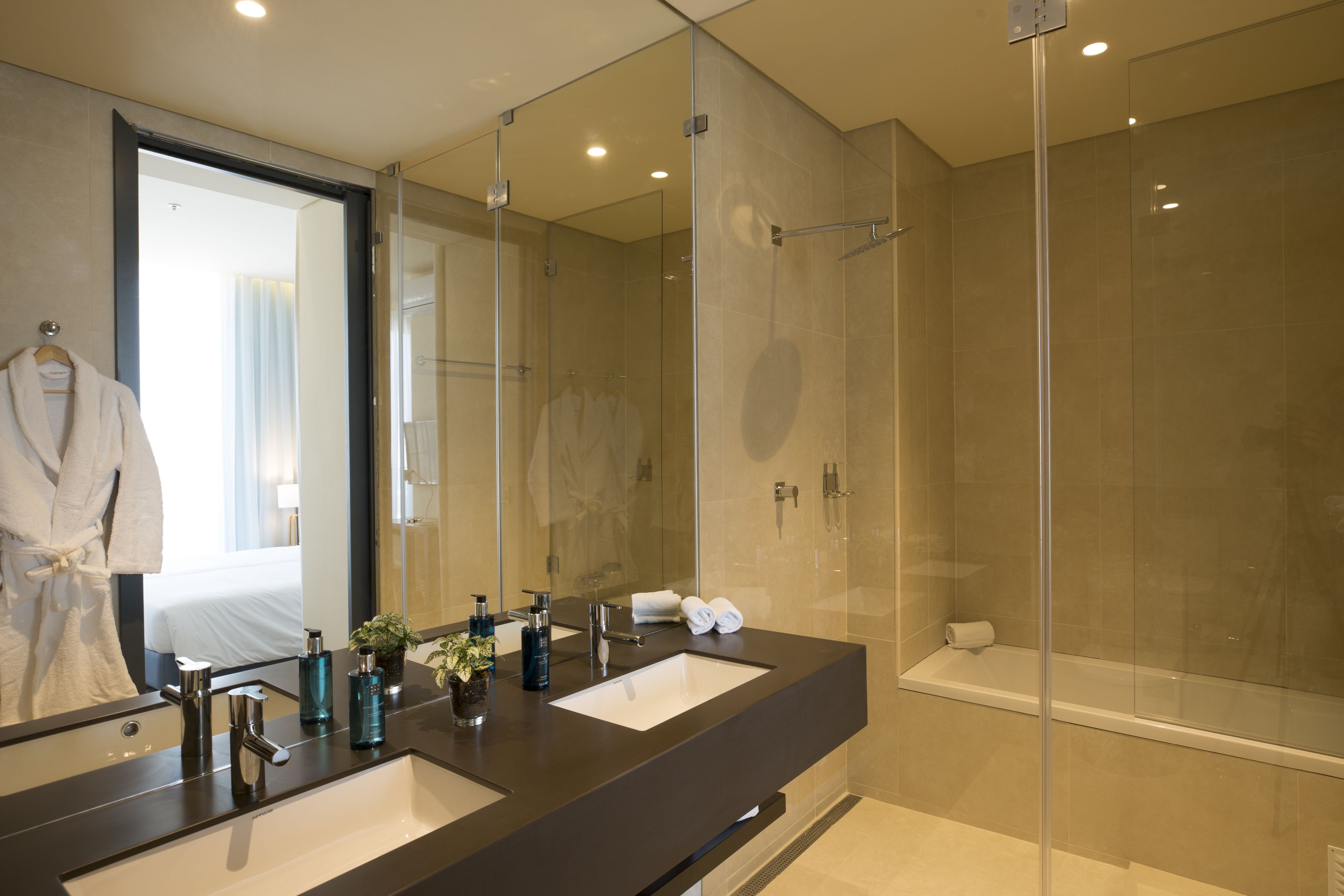 Un baño moderno con un espejo grande, dos lavamanos, una ducha y una bañera.