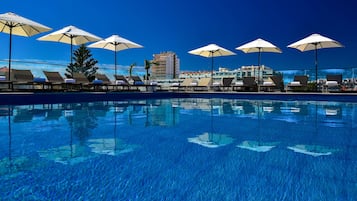 Una piscina techada, una piscina al aire libre, sombrillas