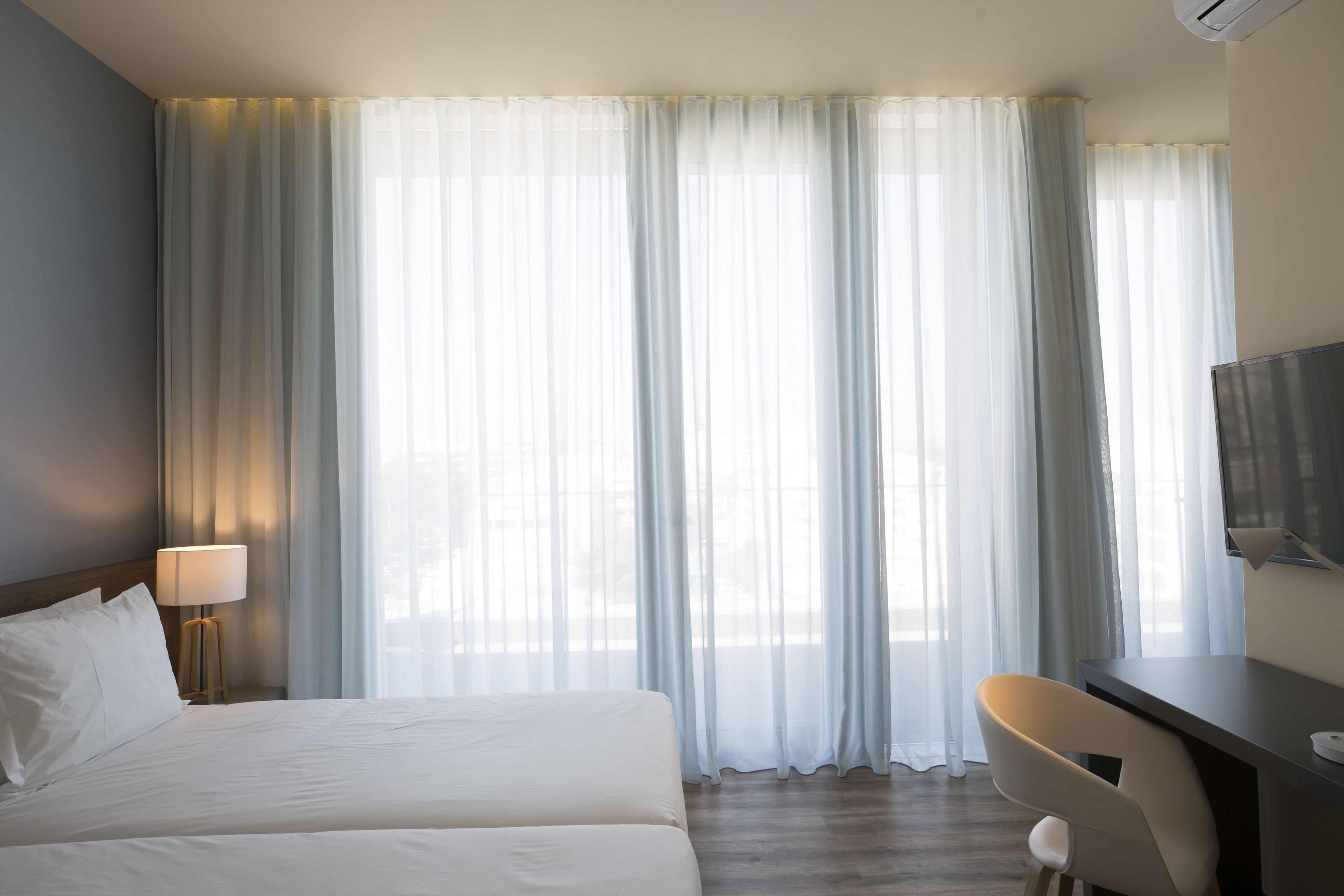 Una camera d'albergo con un letto, una scrivania, una sedia e una televisione.