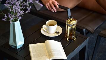 A table with a book, a cup of tea, and a coffee maker.