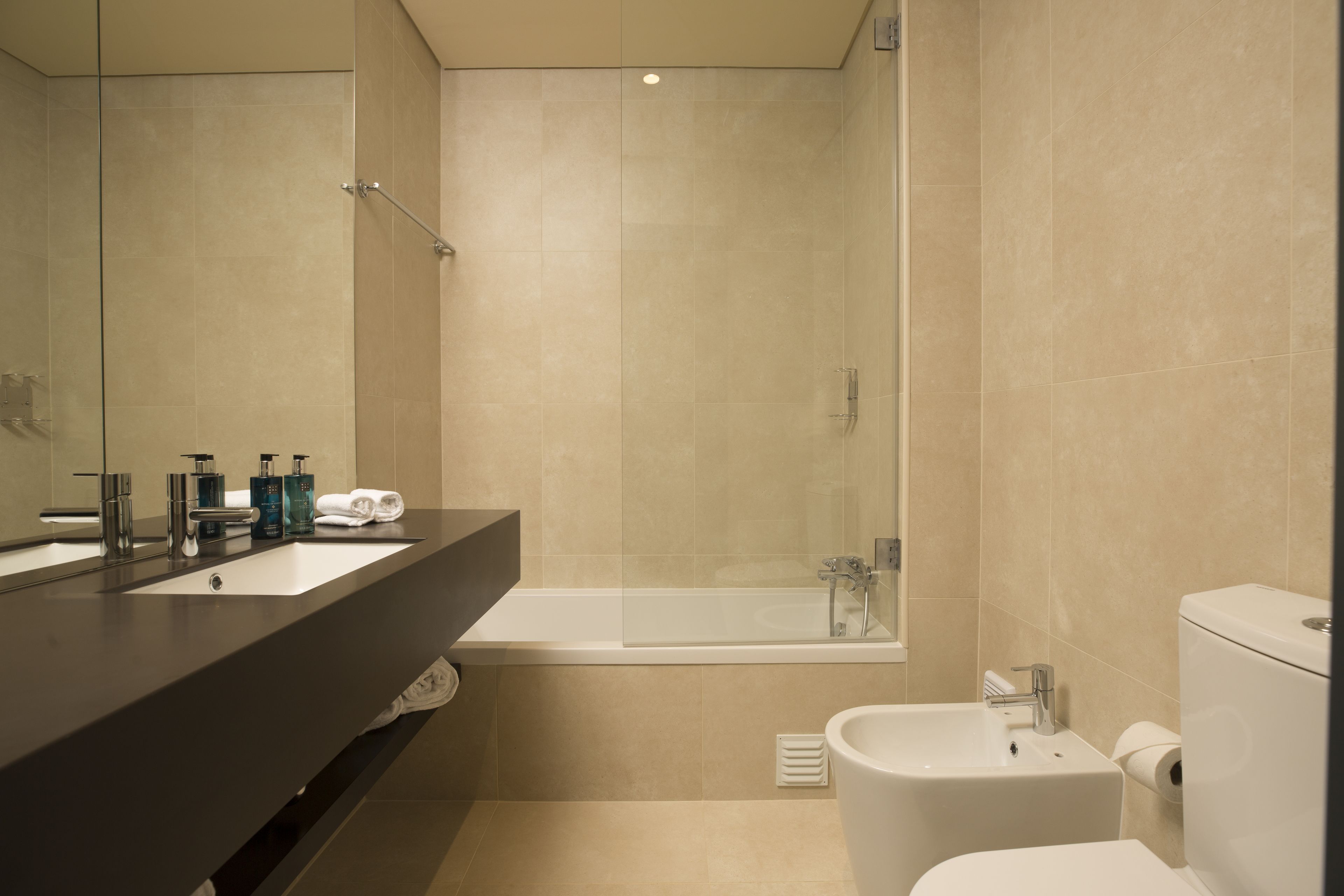 Een moderne badkamer met een bad, een separaat wastafel en een toilet.