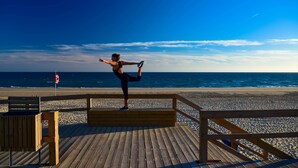A wooden deck with a lifeguard stand and a bench, overlooking a beach with a clear sky. - The Prime Energize Hotel & Spa (Vila Real Santo Antonio)