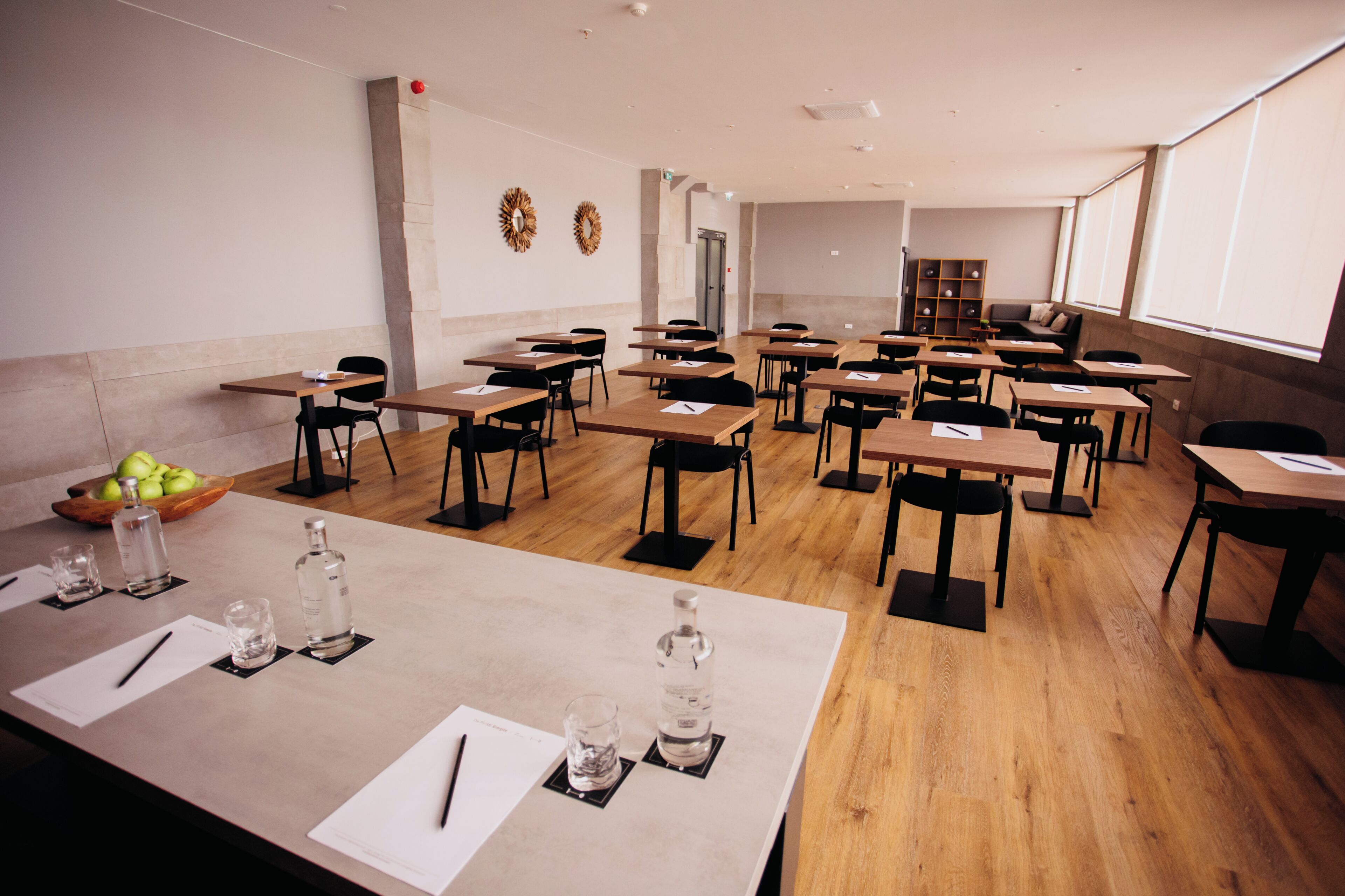 A classroom with desks, chairs, and a wooden floor.