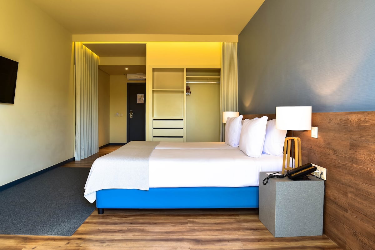 A hotel room with a bed, bedside table, lamp, and a walk-in closet.