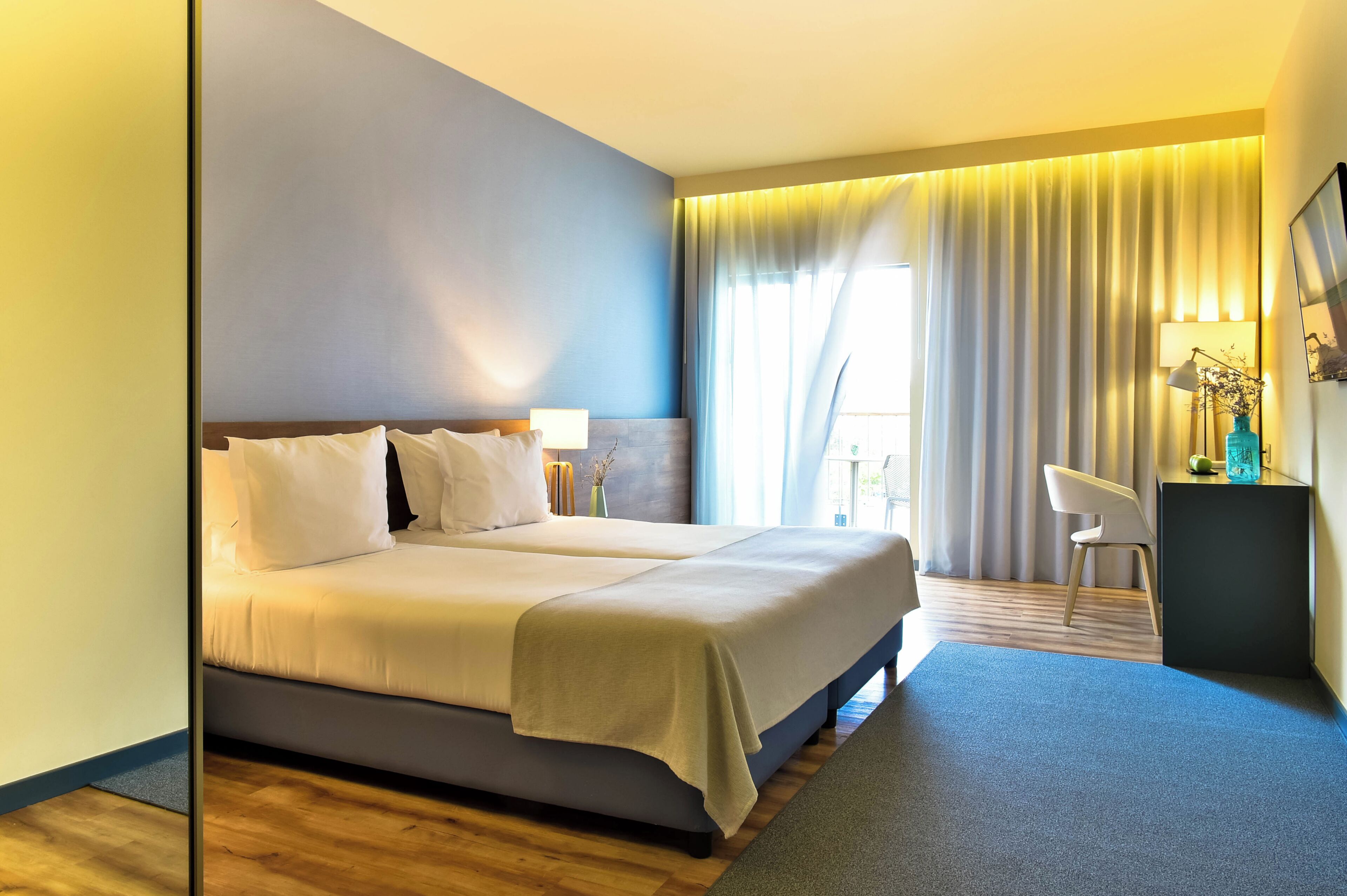 A hotel room with a large bed, bedside tables, a desk, and a chair.