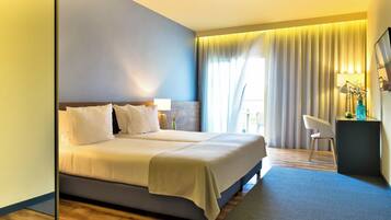 A hotel room with a large bed, bedside tables, a desk, and a chair.