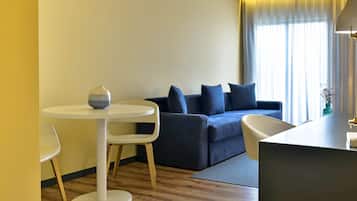 Een moderne woonkamer met een ronde witte tafel, een donkerblauwe bank met meerdere kussens en een witte fauteuil.