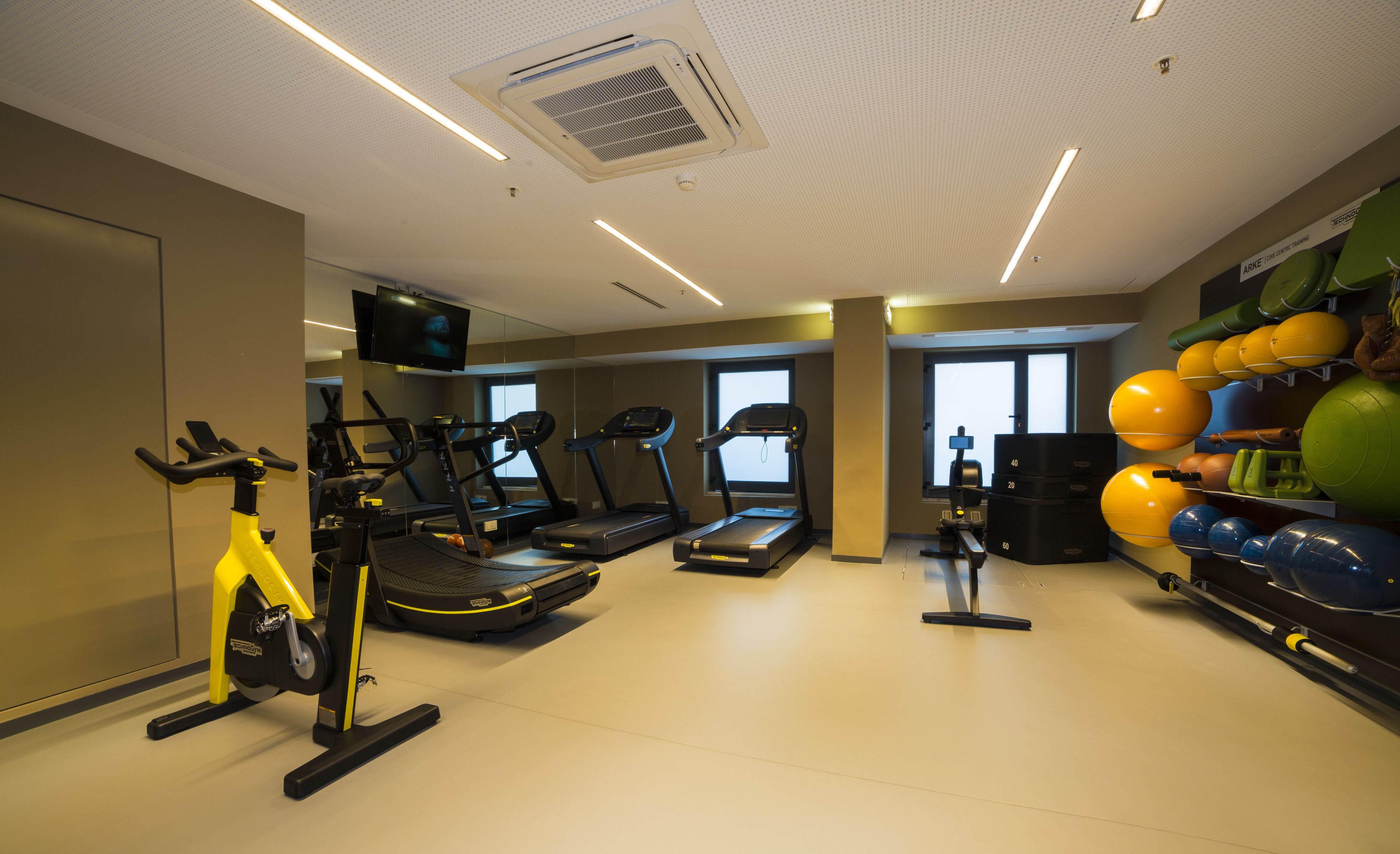 Un gimnasio con cintas de correr, bicicletas estáticas y pelotas de ejercicio.