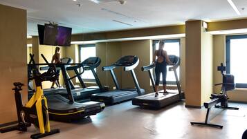 A gym with treadmills, an exercise bike, and a TV screen.