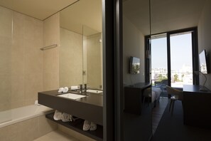 A modern bathroom with a bathtub, a large mirror, and a vanity with a sink.
