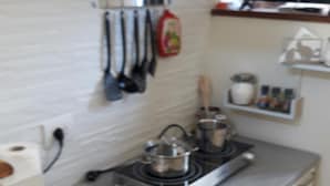 Een keuken met een fornuis, pannen, een waterkoker en een magnetron. Er zijn kasten en een aanrecht.
