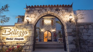 Un arco de piedra con un cartel que indica 'Bellezza Hotel Alghero'.