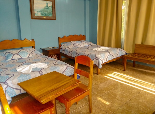 A room with two wooden beds with patterned bedding, a wooden table, a chair, a nightstand, and a framed picture on the wall. - Arenal Xilopalo (La Fortuna)