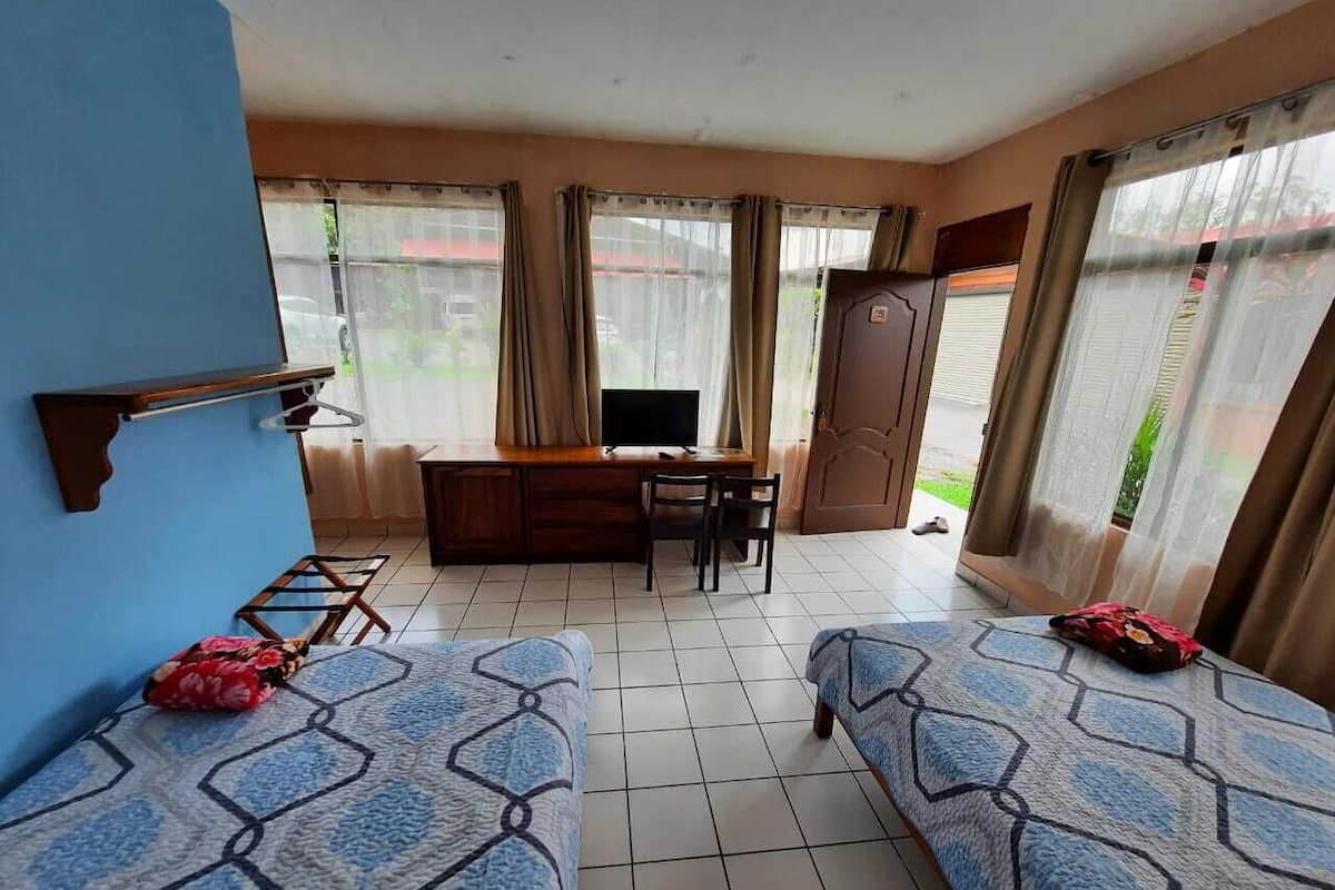 Une chambre avec deux lits, un bureau, une télévision et une armoire.