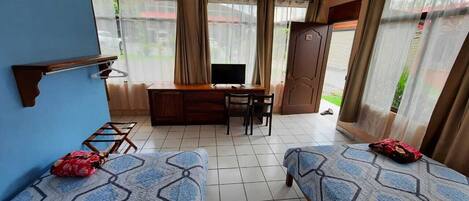 A room with two beds, a desk, a TV, and a wardrobe.