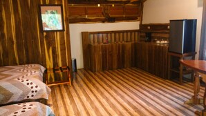 A room with wooden paneling, a bed with a patterned blanket, a television, and a wooden table.