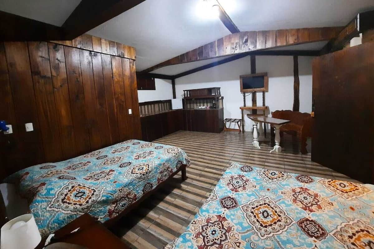 Une chambre avec deux lits, des murs en bois, un bureau et une chaise.