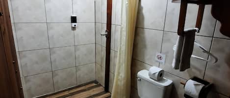A bathroom with a shower, toilet, and a towel rack.