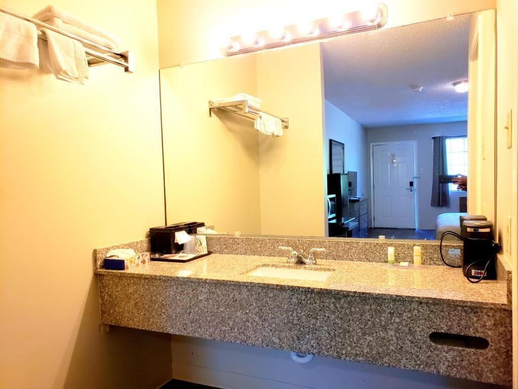 A bathroom with a granite countertop, a sink, a coffee maker, and a towel rack.
