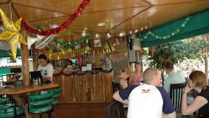 Un restaurant avec un plafond en bois, des tabourets de bar verts et une décoration festive.