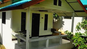 Un edificio de una sola planta con porche cubierto, un pequeño espacio de estar al aire libre y una puerta que da al interior.