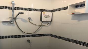 Una ducha con cabezal de ducha de mano y panel de control en la pared.