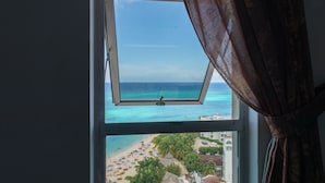 A view from a window overlooking a beach with palm trees and a clear sky. - Montego Bay Club Beach Resort (Montego Bay)