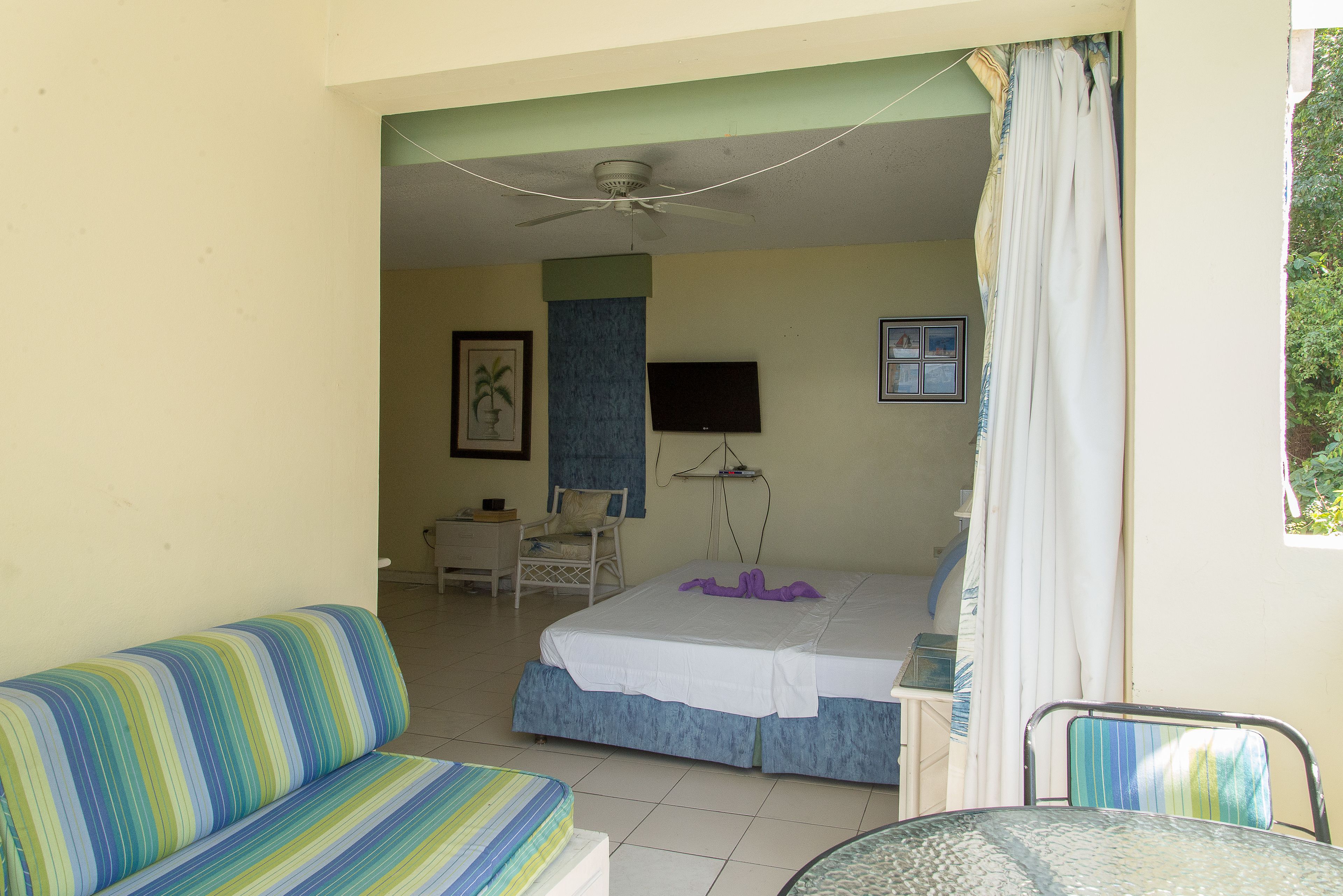 Ein Hotelzimmer mit Bett, Sofa, Fernseher und Deckenventilator.