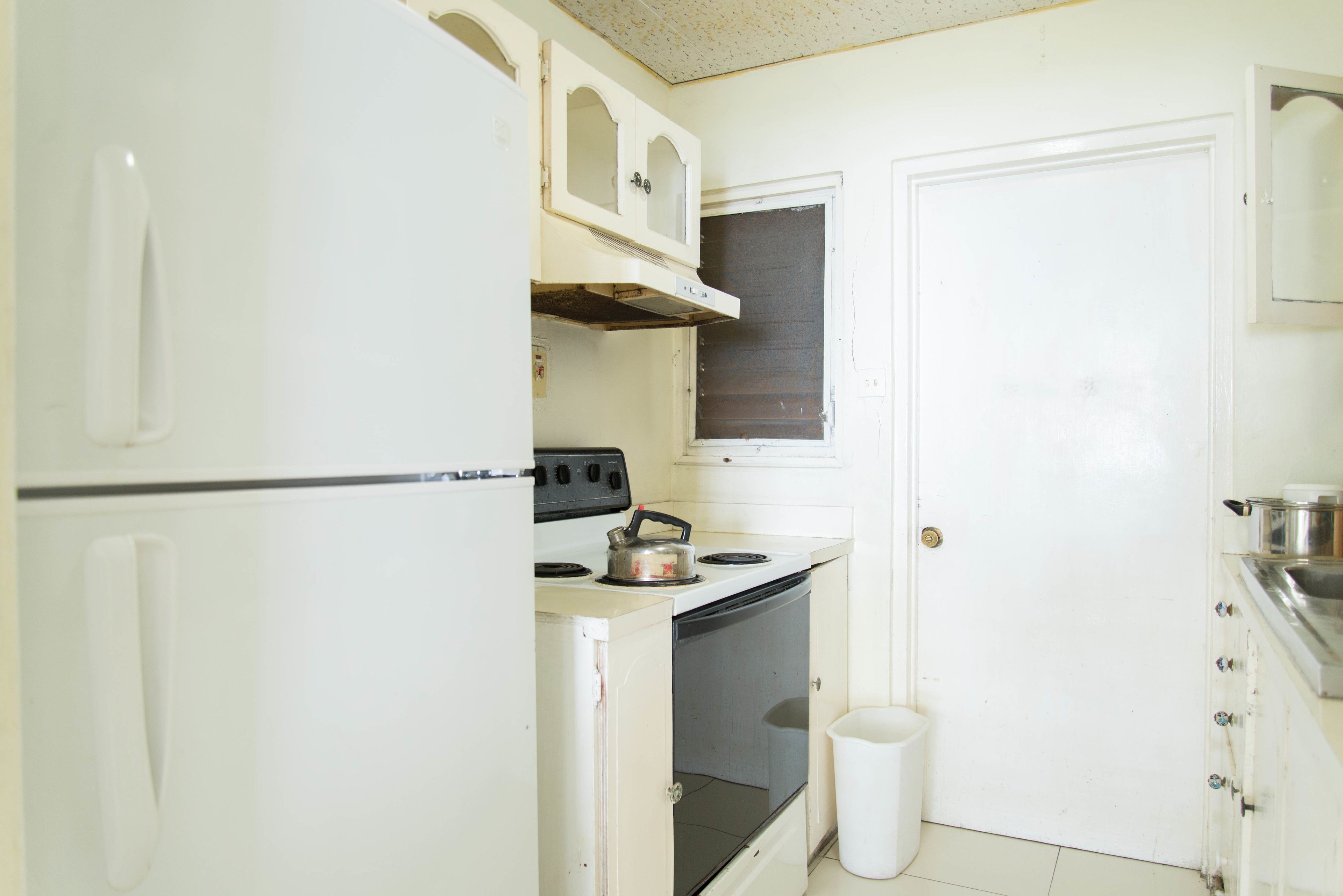 A compact kitchen with white cabinets, a stove, and a sink.
