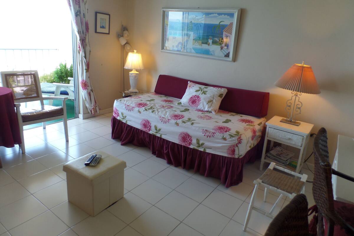 A bedroom with a bed, bedside tables, a chair, a small table, and a window with a view.