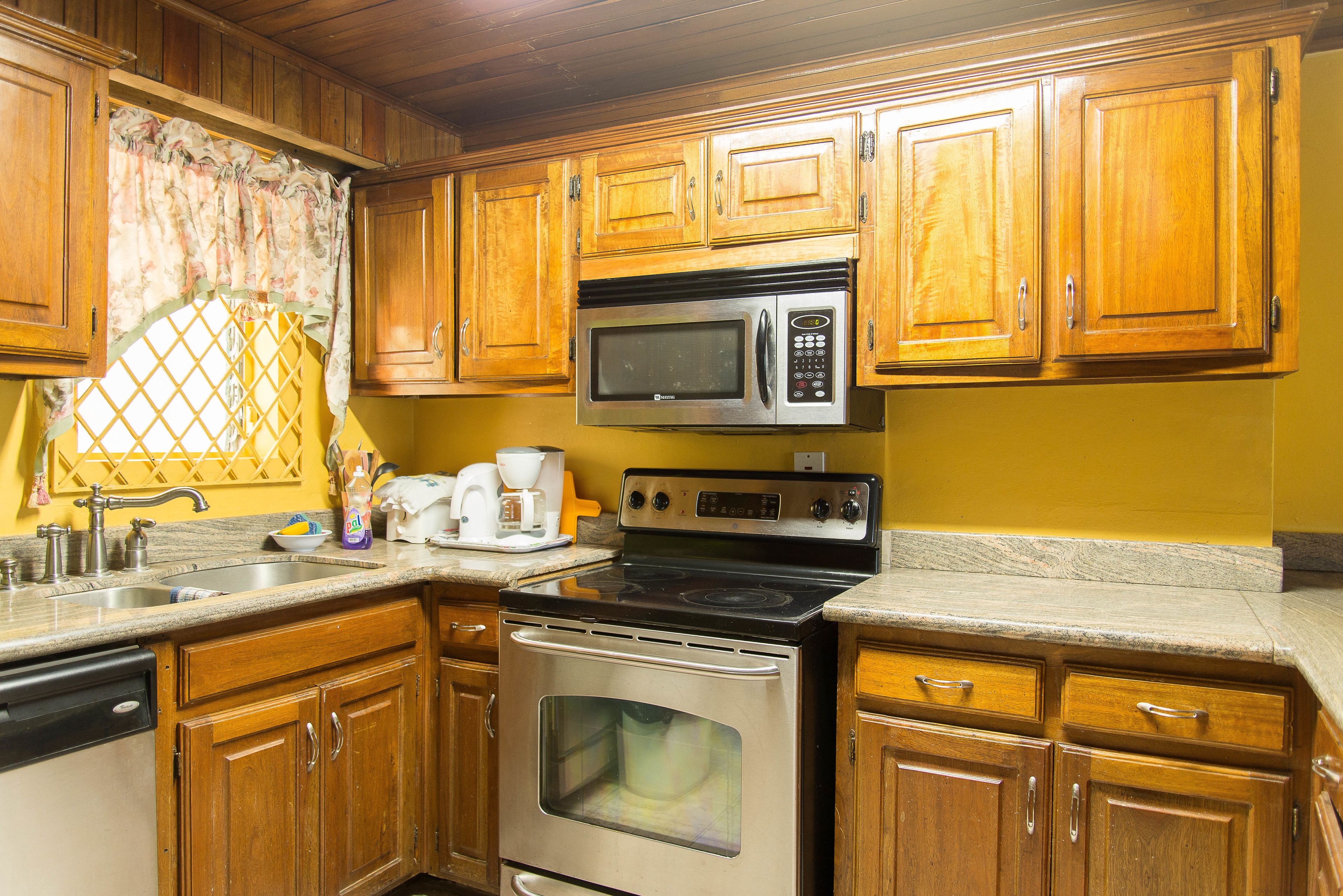 A kitchen with wooden cabinets, a stainless steel microwave, an oven, and a granite countertop.