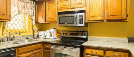A kitchen with wooden cabinets, a stainless steel microwave, an oven, and a granite countertop.