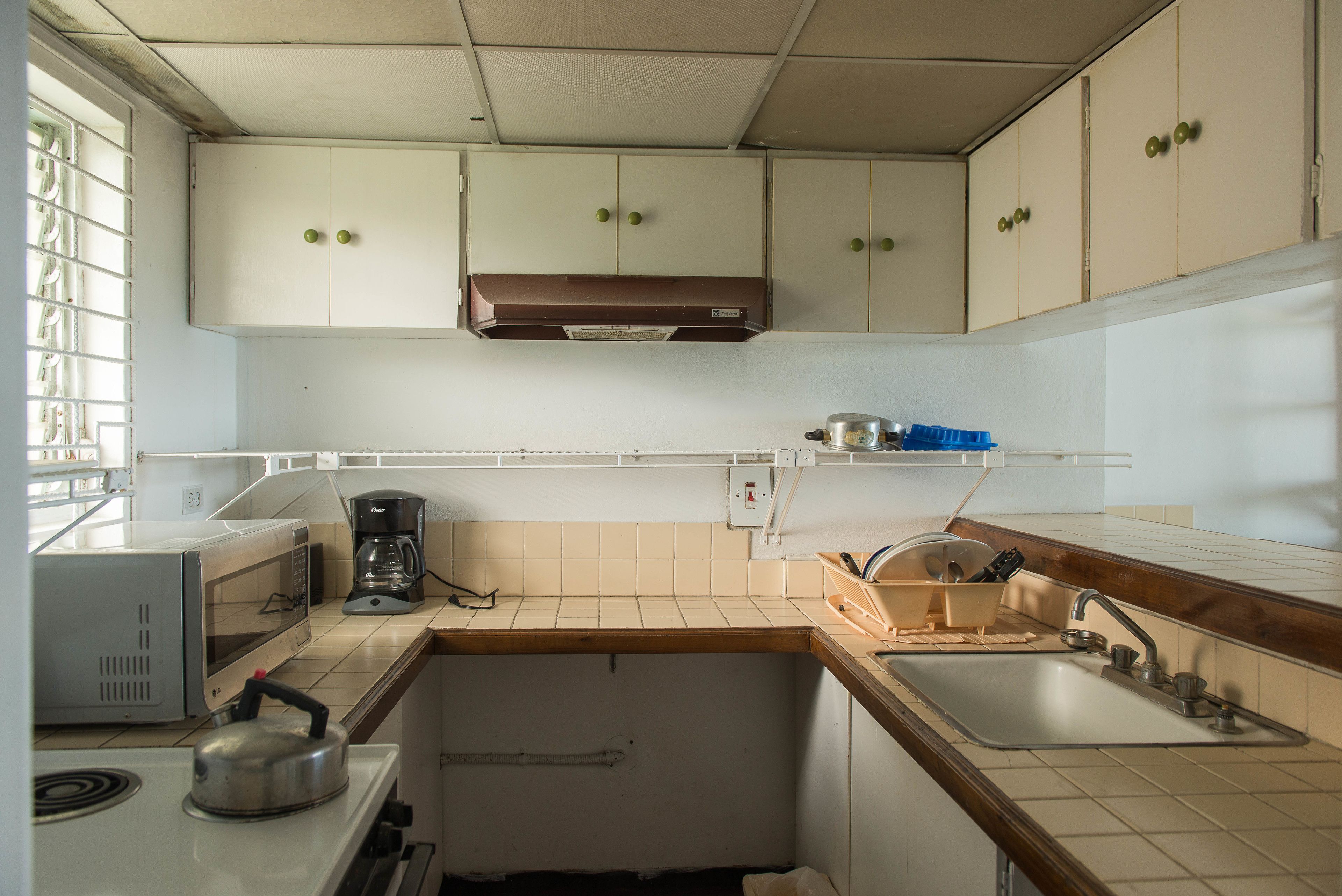Cocina compacta con microondas, cafetera, hervidor y lavabo.