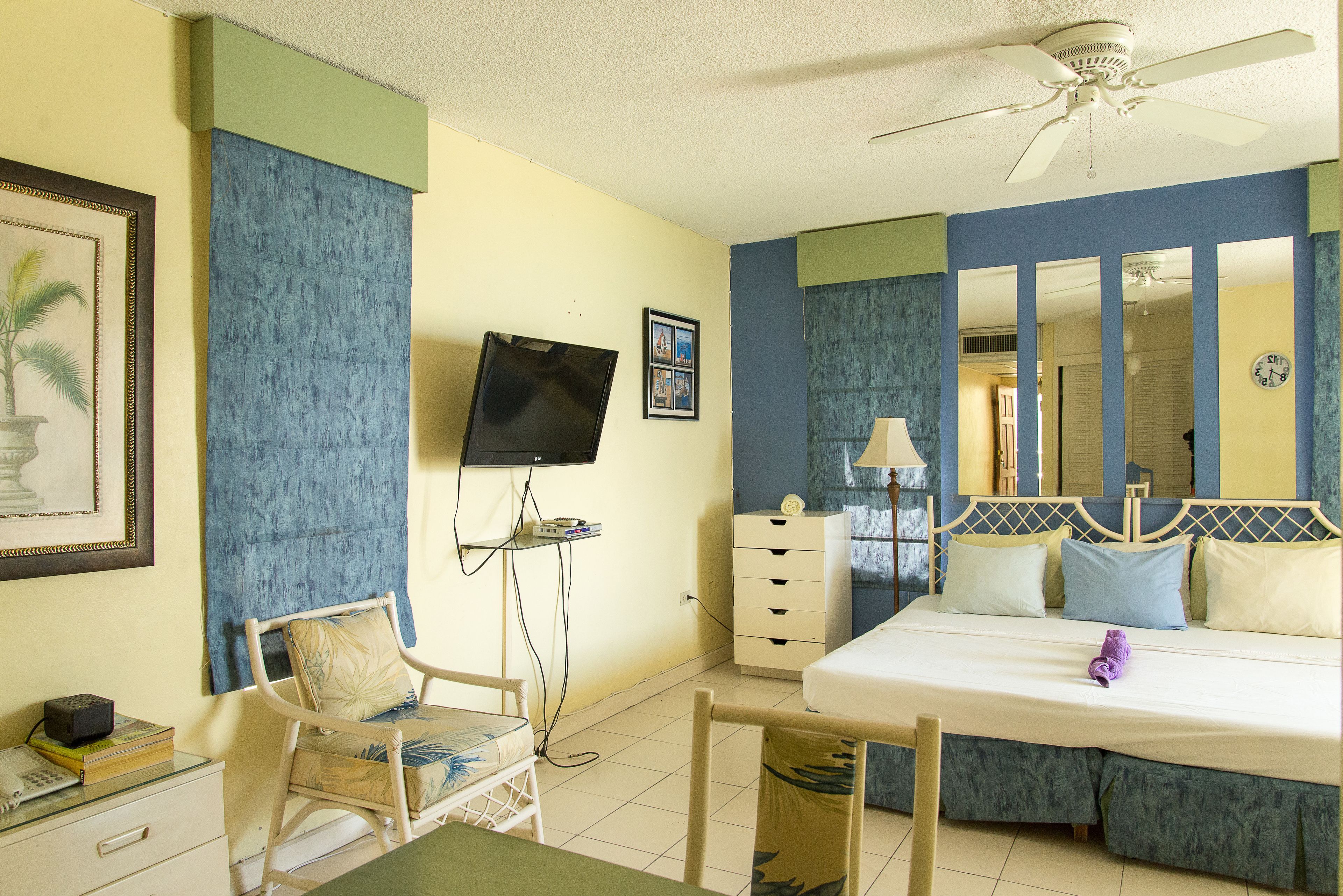 A hotel room with a bed, a desk, a chair, a television, a dresser, and a mirror.