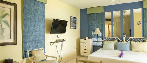 A hotel room with a bed, a desk, a chair, a television, a dresser, and a mirror.
