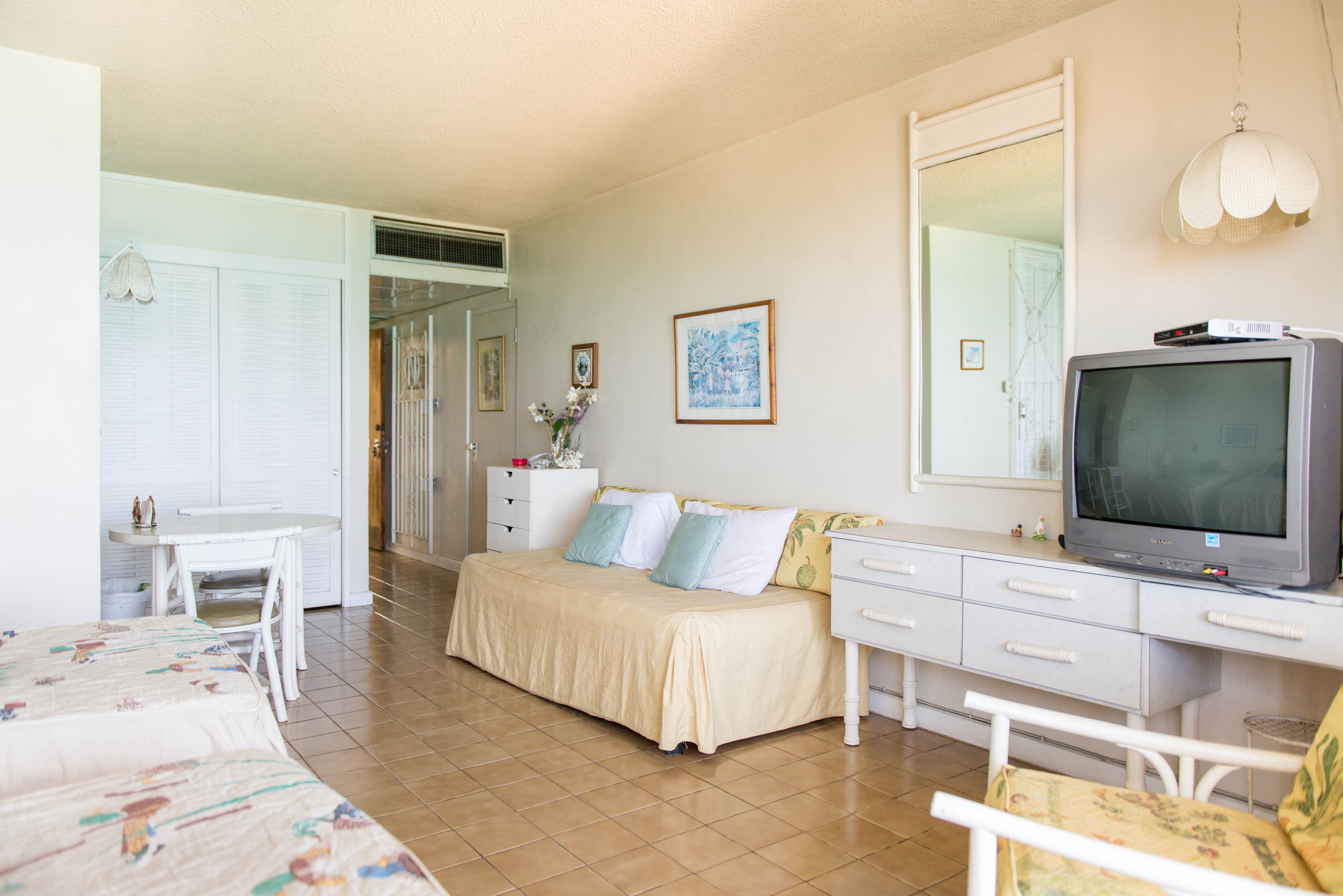 Una camera da letto con un letto, una scrivania, un televisore e un comò.