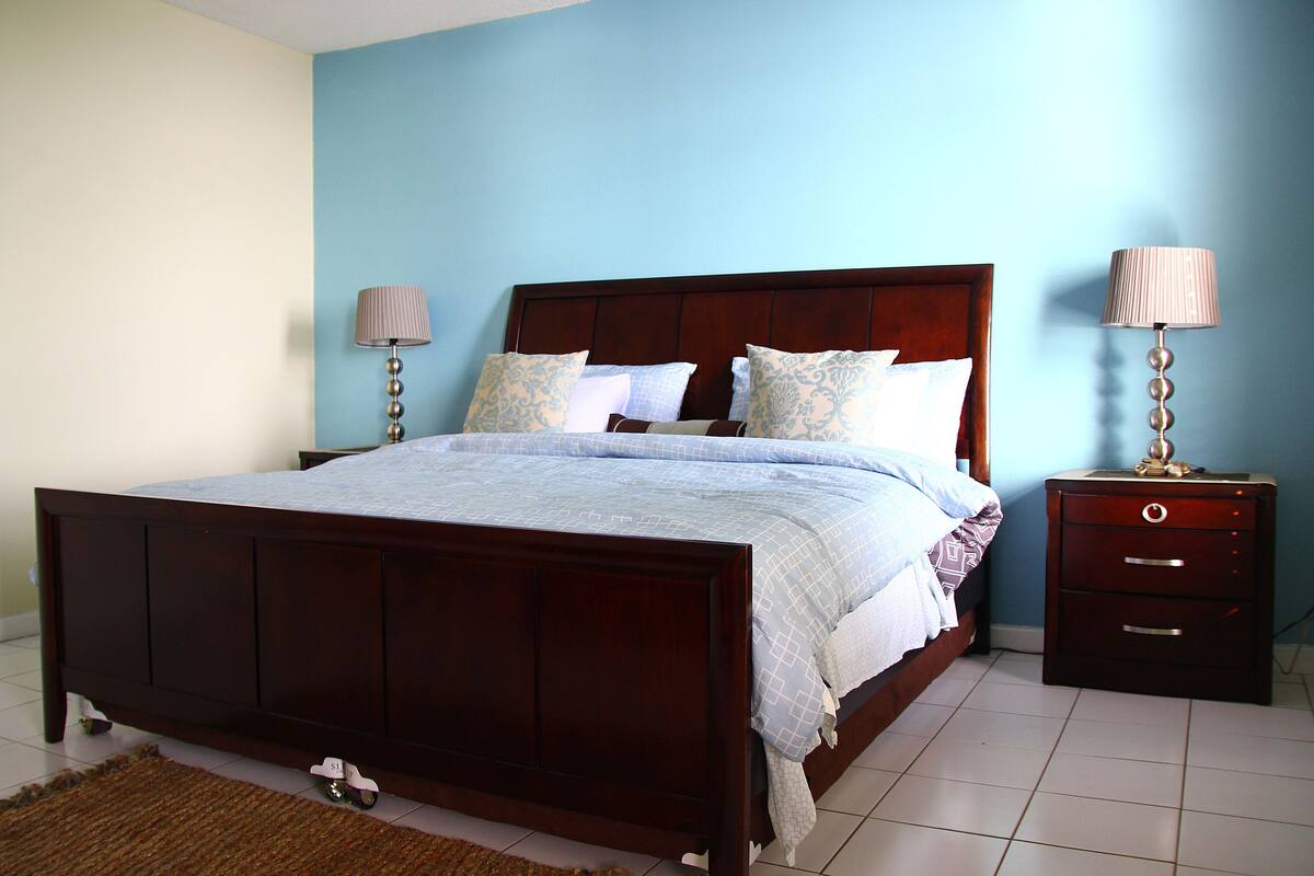 A bedroom with a wooden bed, two bedside tables with lamps, and a patterned bedspread.