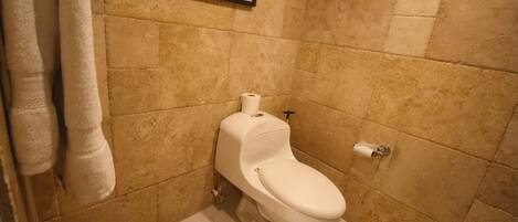 A bathroom with a toilet, a towel rack, and a framed picture on the wall.