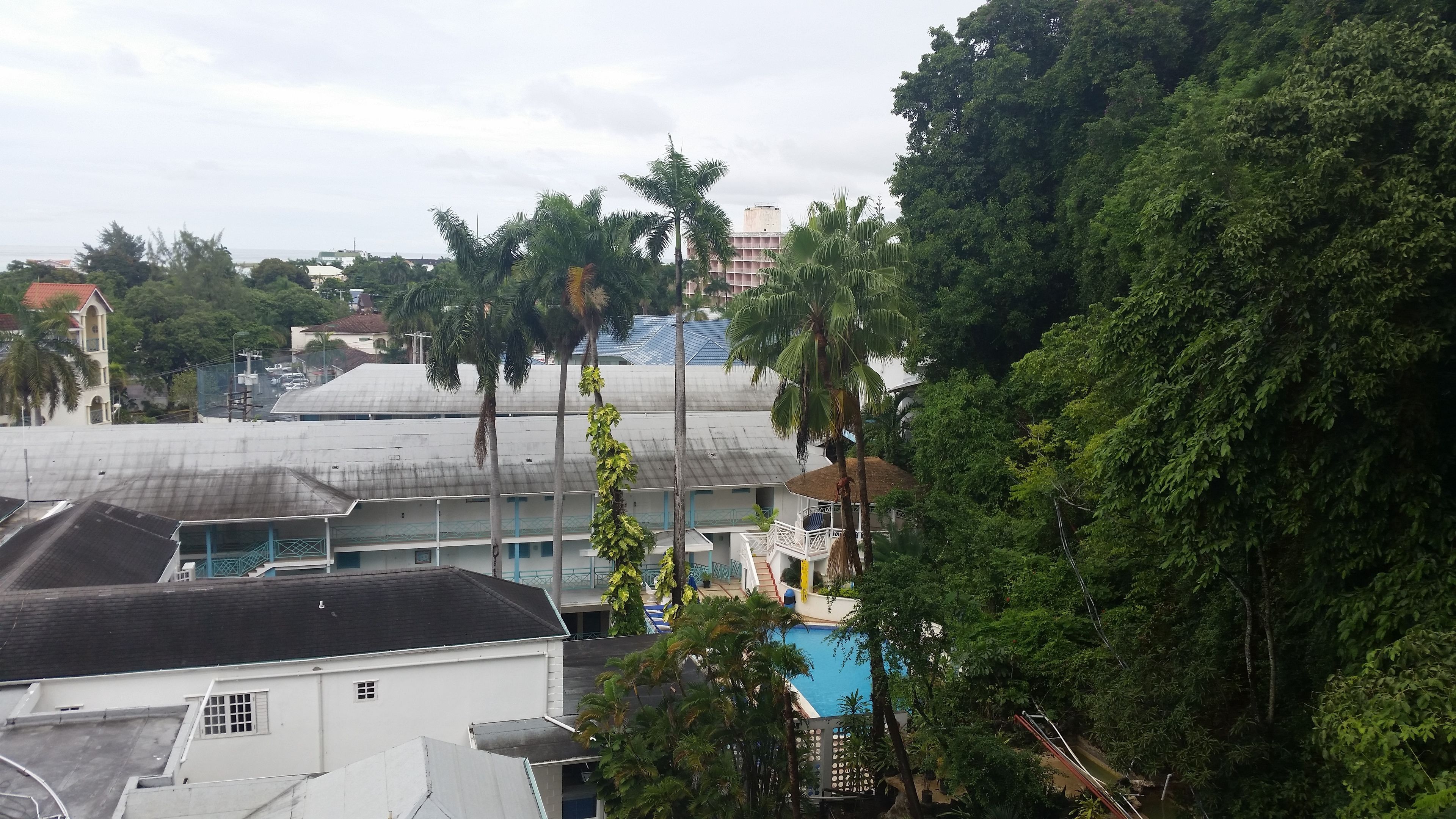 A residential area with a white building featuring a balcony and a pool.